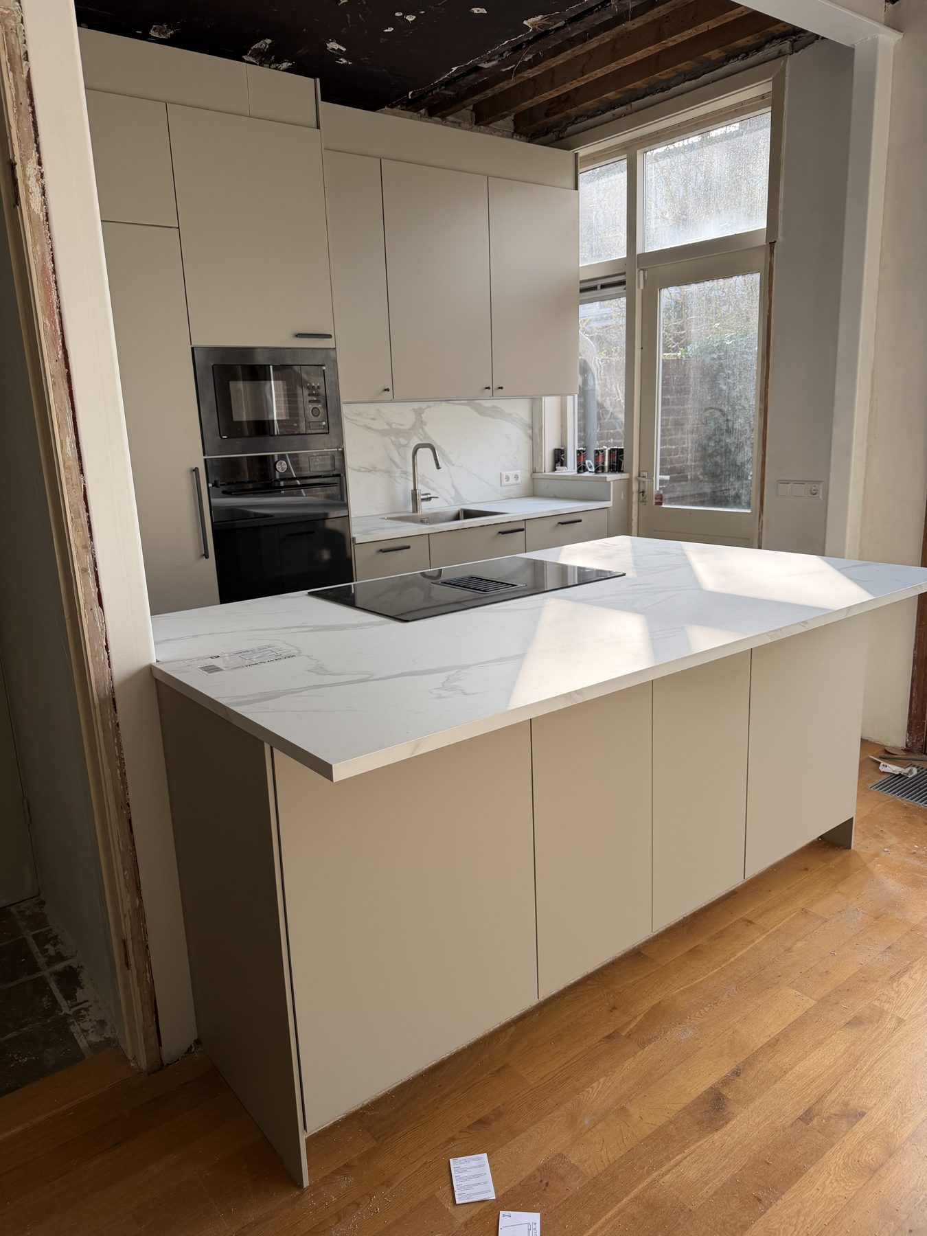 Beige keuken met kookeiland en marmerlook werkblad, door ons gemonteerd